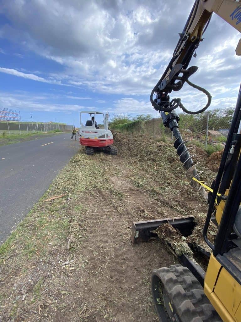 Crew clearing and preparing the ground before chain-link fence installation in Kapolei.