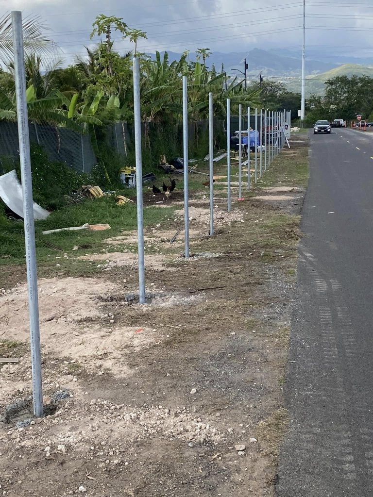 Newly set metal fence posts aligned for chain-link fence installation in Kapolei.