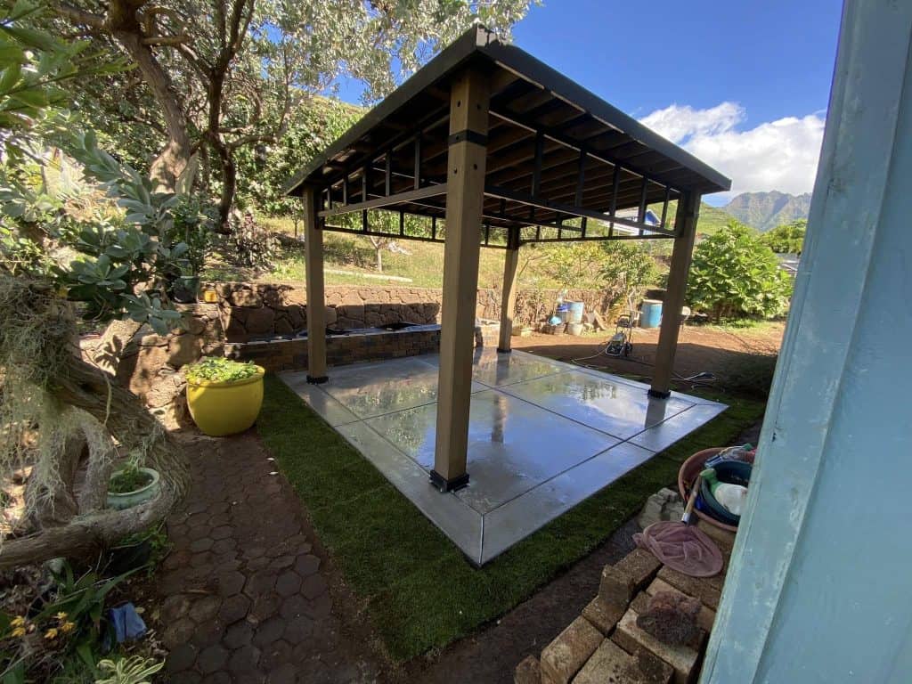 Newly built outdoor gazebo on a smooth concrete slab surrounded by landscaped yard in Oahu.
