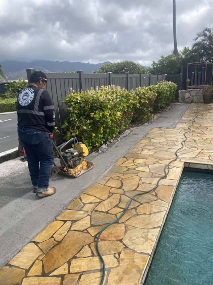 Crew compacting the base layer to prepare for artificial turf installation.