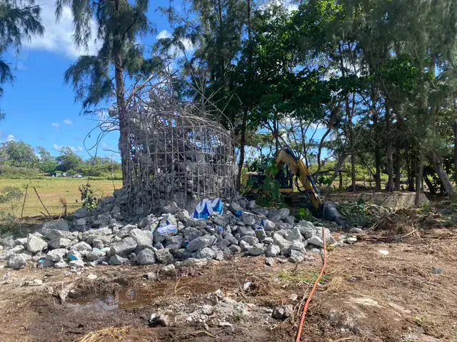 Excavator breaking apart remaining concrete structures in Kahuku.