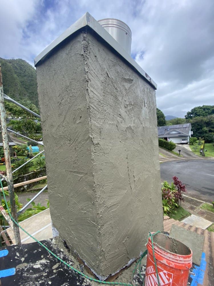 Chimney fully covered in cured scratch coat prior to blue rock veneer installation