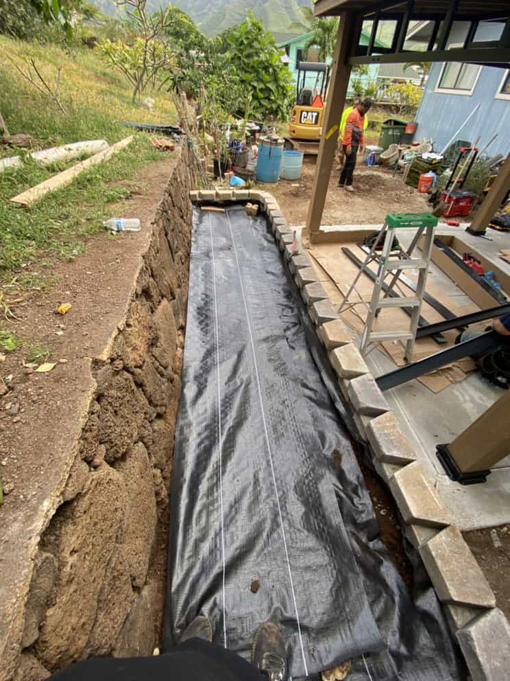 Weed barrier installed behind retaining wall for long-term stability.