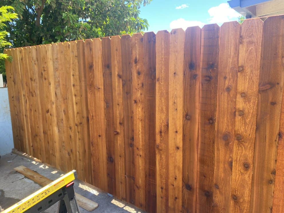 near-complete wood privacy fence shown from front angle during final installation